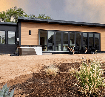 Modern custom home exterior with large windows, wooden paneling, and landscaped yard, showcasing Oak-n-Crete's construction quality and design aesthetics.