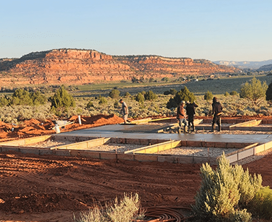 Construction team working on building foundation in desert landscape, showcasing the initial phase of custom home construction by Oak-n-Crete.
