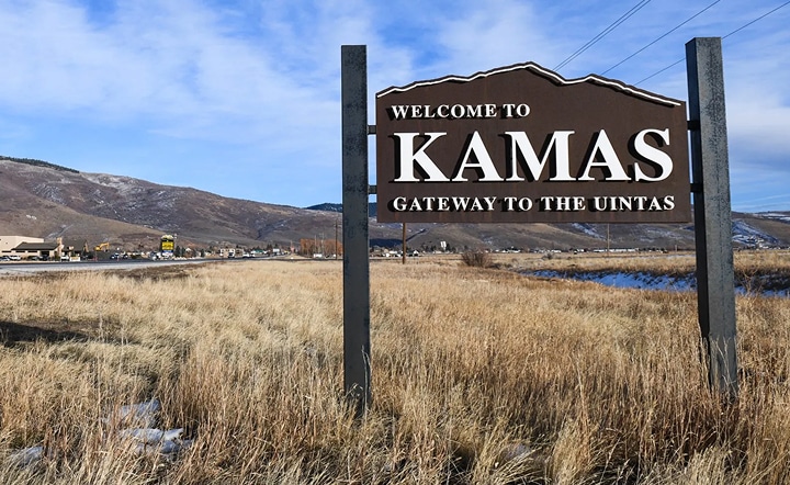 kamas Welcome sign for Kamas, Utah, highlighting "Gateway to the Uintas," with surrounding mountains and grassland, relevant to building trends in the Wasatch region.